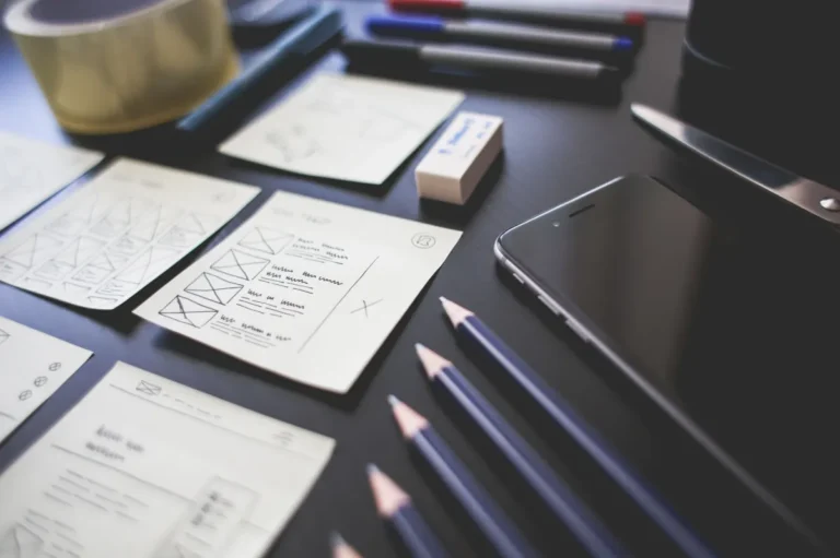 Paper wireframes and pencils on a designer’s desk