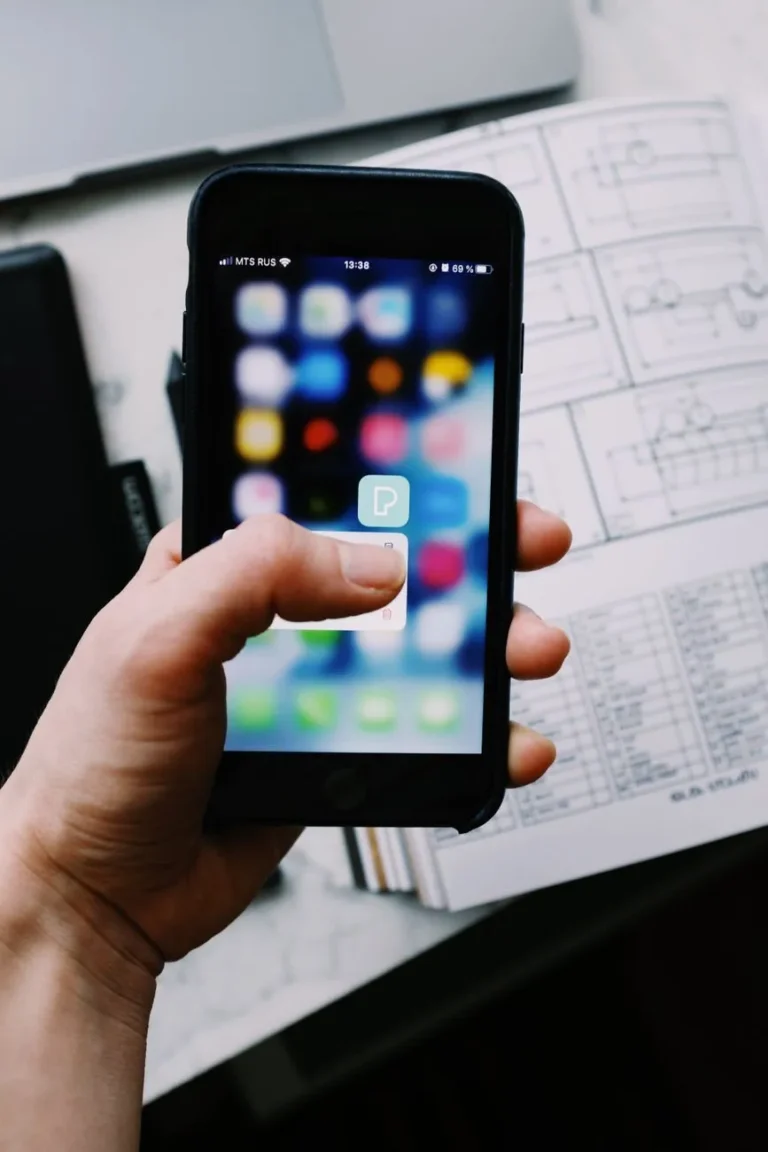 Hand holding a smartphone over app sketches