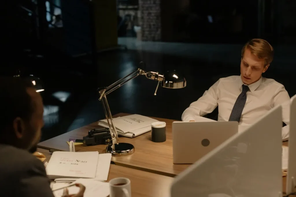 Two professionals reviewing documents in an office at night