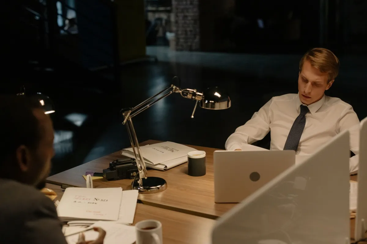 Two professionals reviewing documents in an office at night